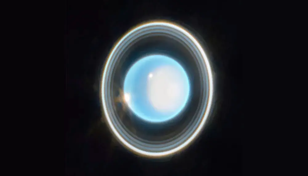 Vue infrarouge saisissante d'Uranus par le télescope James Webb, montrant ses anneaux concentriques brillants et des tempêtes lumineuses sur la surface.